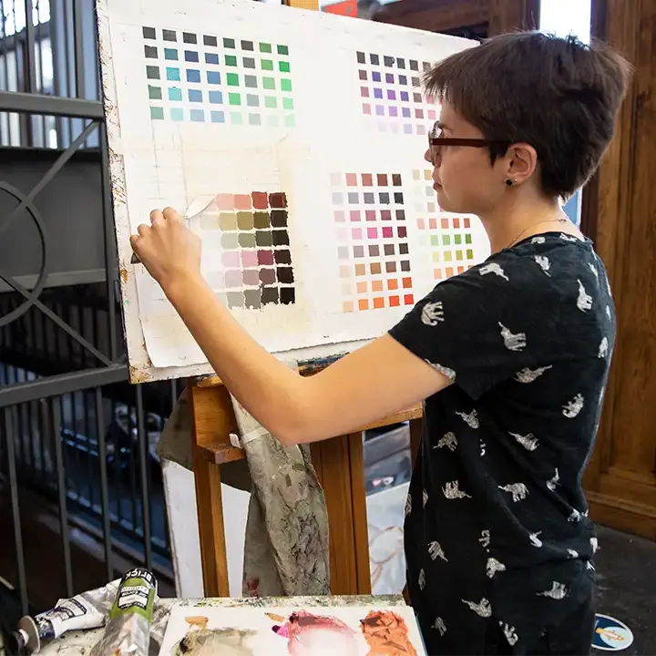 Person standing in front of painted color swatches.